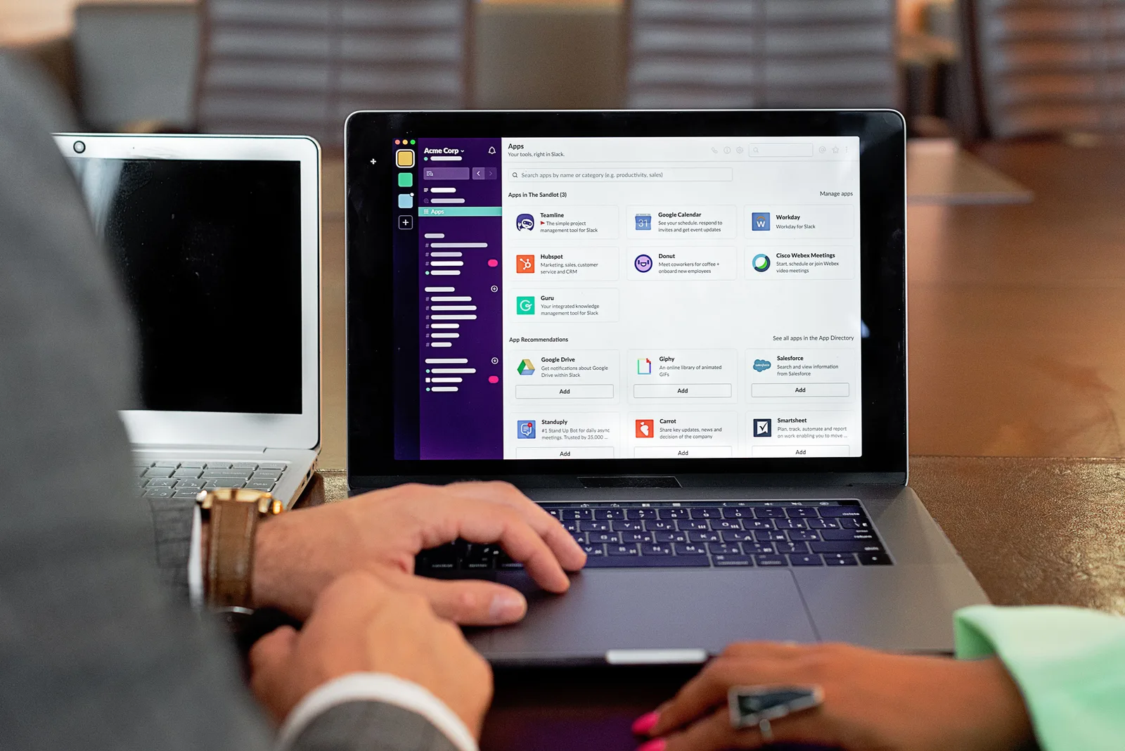 Two professionals collaborating using laptops and communication software in a business setting. What questions do sales enablement teams ask most often?