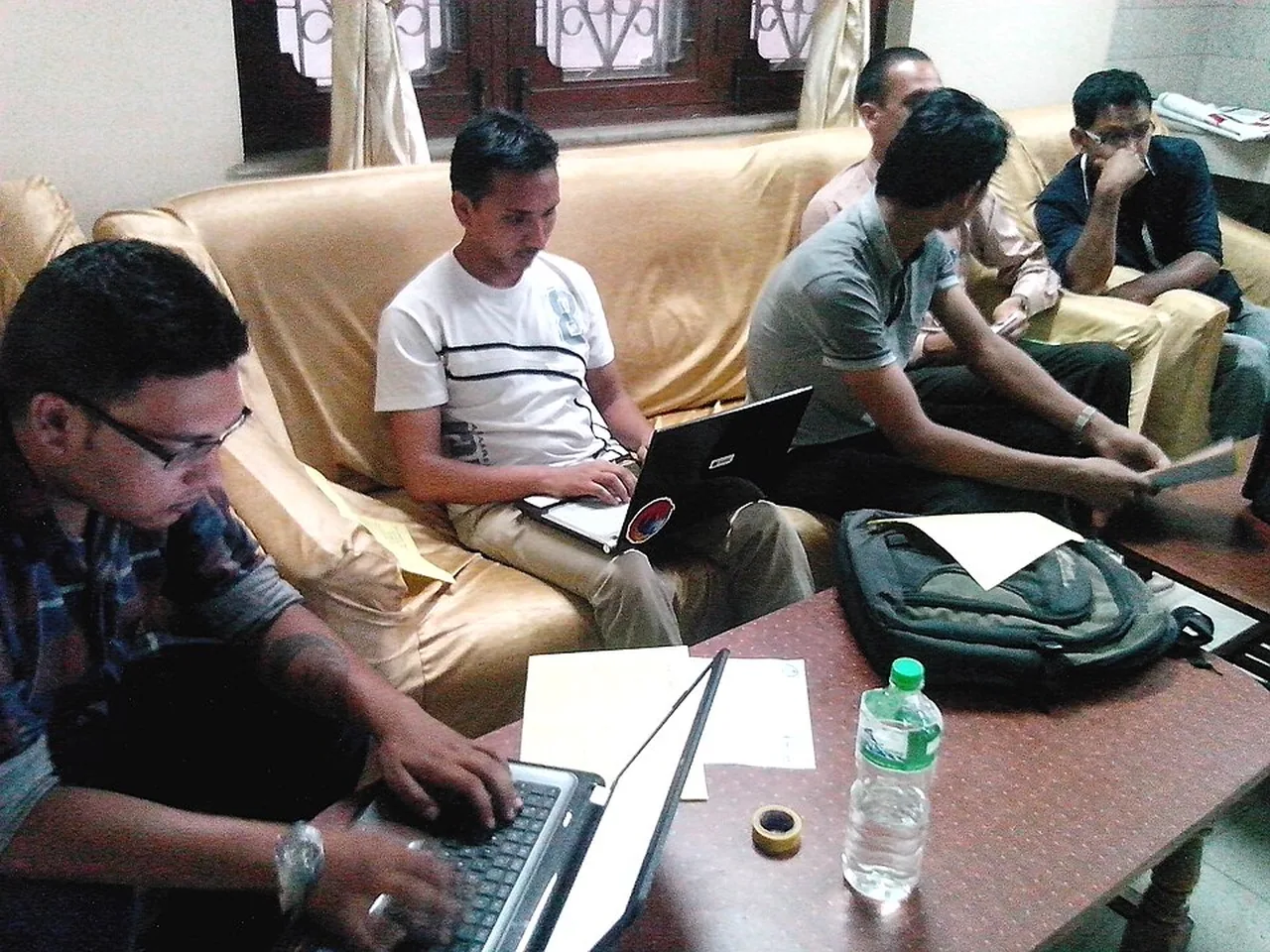 Several members of a social media team work with laptops and notes during a press meeting.